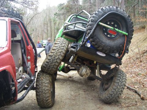 1978 Ford Bronco - A heavily modified green off-road vehicle is shown from the rear, with a red vehicle to its left.
