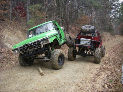 1978 Ford Bronco - Two heavily modified trucks navigate a wooded trail.