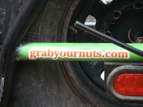 1978 Ford Bronco - A green bar with a humorous website address is visible on a vehicle part, near a tire and taillight.