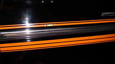 1979 Ford F-150 - Side view of a black truck door orange racing stripes and chrome trim.