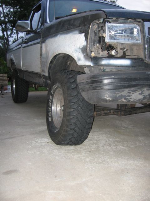 1995 Ford F-150 - This truck's front end shows damage and repair work, with a missing headlight and body filler.