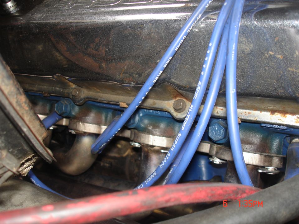 Blue Accel spark plug wires and exhaust manifold on blue-painted engine head in a 1979 Ford Bronco
