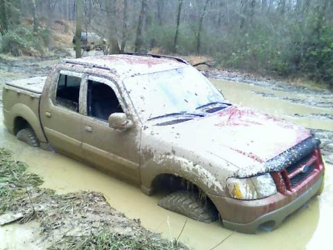 2002 Ford Sport Trac - This 2002 Ford Sport Trac is deeply stuck in mud, with another vehicle visible in the wooded background.