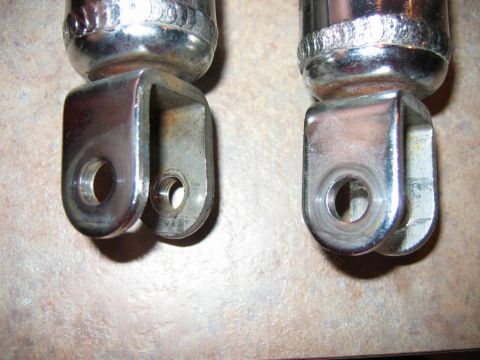 1985 Ford LTD Crown Victoria - Two chrome shock absorbers are shown, each with a U-shaped mounting bracket at the bottom.