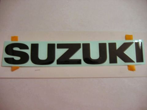 1985 Ford LTD Crown Victoria - A Suzuki emblem is shown, attached to a surface with orange tape.