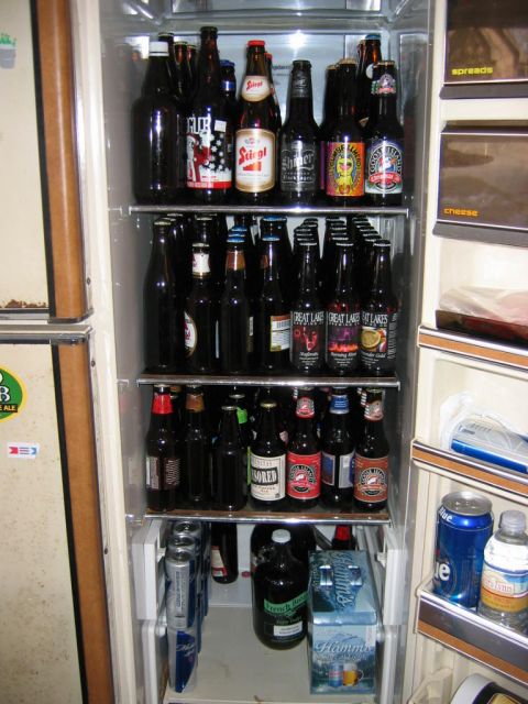 1985 Ford LTD Crown Victoria - A refrigerator is stocked with numerous bottles and cans of beer, along with some other items.