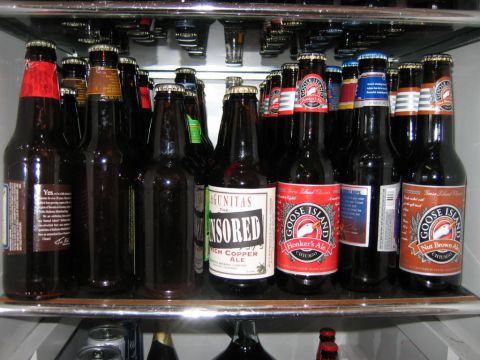 1985 Ford LTD Crown Victoria - A variety of beer bottles are chilled on a refrigerator shelf, with some labels clearly visible.