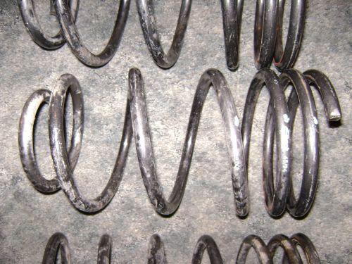 Several rusty automotive coil springs laid out on a concrete floor