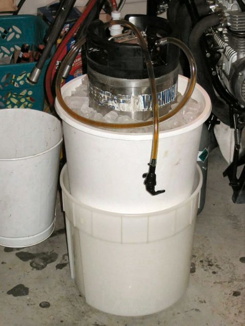 1985 Ford LTD Crown Victoria - A beer keg is set up on ice in buckets, with a portion of a motorcycle engine visible in the background.