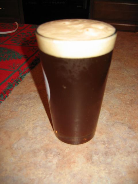 1985 Ford LTD Crown Victoria - A glass of dark beer with foam sits on a counter next to a festive tablecloth.