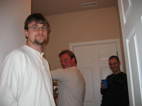 1985 Ford LTD Crown Victoria - Three men are gathered indoors, with one man in the foreground and two others in the background near a doorway.
