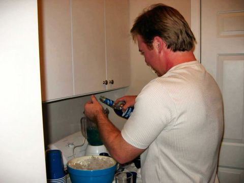 1985 Ford LTD Crown Victoria - Man preparing a blue beverage in a blender in a kitchen setting.