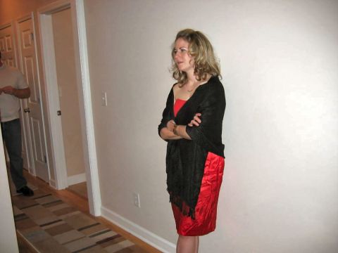 1985 Ford LTD Crown Victoria - A woman stands with her arms crossed, wearing a red dress and a black shawl.