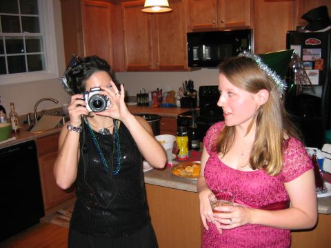 1985 Ford LTD Crown Victoria - Two women celebrate in a kitchen, one documenting the moment with a camera.