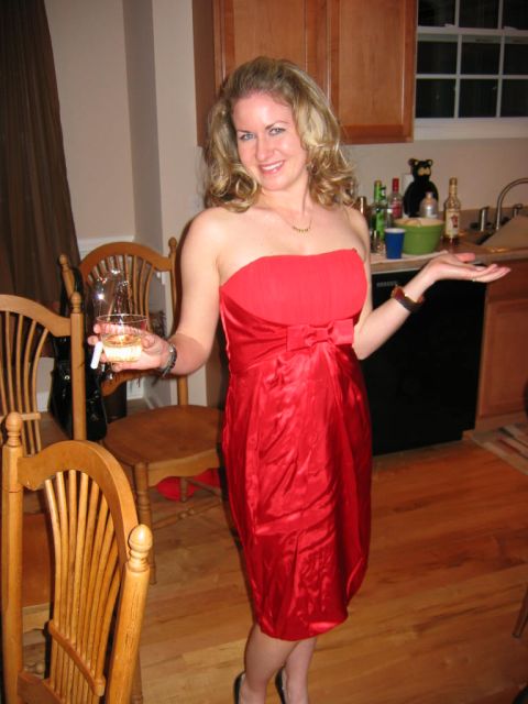 1985 Ford LTD Crown Victoria - A woman in a red dress poses for a photo while holding a drink and standing in what appears to be a kitchen or dining area.
