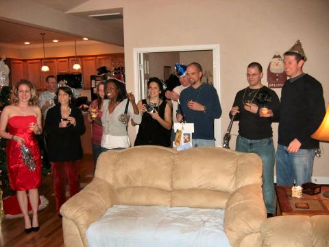 1985 Ford LTD Crown Victoria - A group of friends and family celebrate a holiday event indoors, holding drinks and cameras.