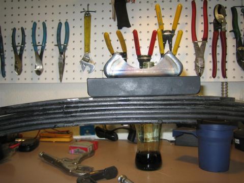 1987 Suzuki Samurai - A collection of tools hangs above a vehicle leaf spring on a workbench.