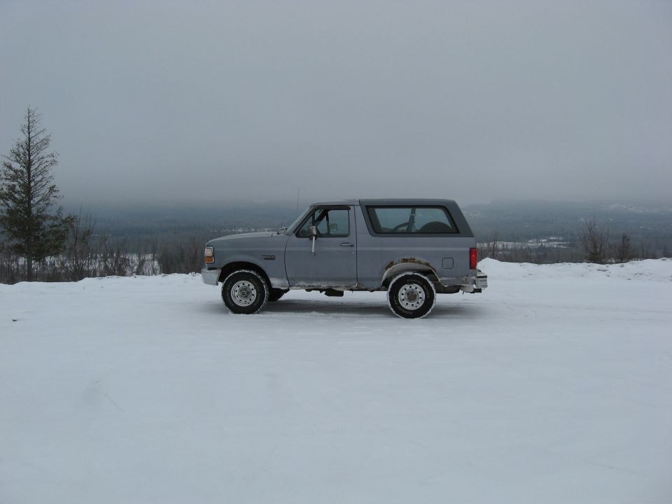 Gray 1992 Ford Bronco parked on a snowy hill, side view