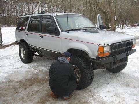 1979 Ford Bronco - A silver Ford Explorer, likely from the early 1990s, is shown with large off-road tires and a custom front bumper.