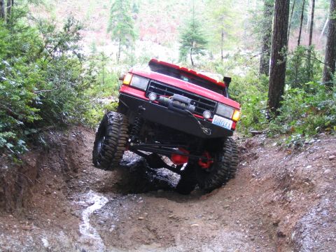 1989 Ford Bronco - This modified SUV navigates a challenging off-road trail with one wheel high in the air.