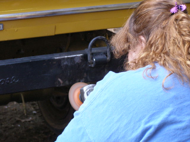 Yellow vehicle bumper being polished by a person