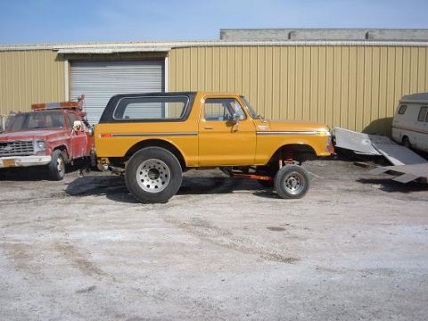 1978 Ford Bronco - Side view of a lifted 1978 Ford Bronco next to a tow truck.