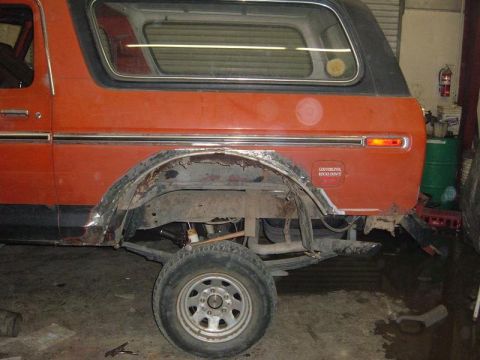 1978 Ford Bronco - This orange SUV shows significant rust around the rear wheel well, with a humorous sticker on the fender.