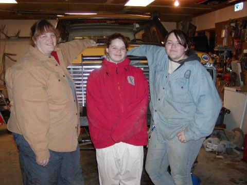 1978 Ford Bronco - Three individuals pose for a photo in front of a large truck, with a workshop environment in the background.