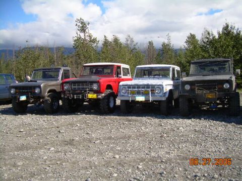 1978 Ford Bronco - Four Ford Broncos are parked together in a gravel lot under a cloudy sky.
