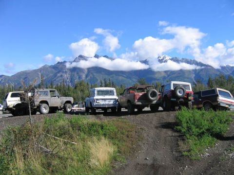 1978 Ford Bronco - A convoy of Ford Broncos, including a 1978 model, are parked on a dirt road with a scenic mountain backdrop.