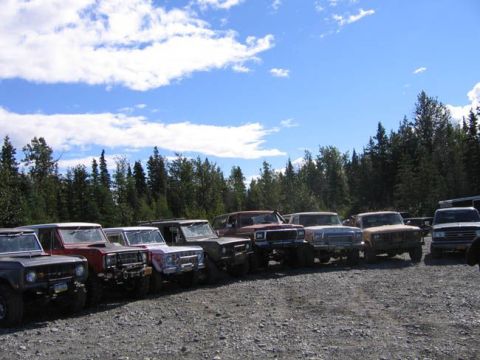 1978 Ford Bronco - Several 1978 Ford Broncos are parked in a row on a gravel lot under a partly cloudy sky.