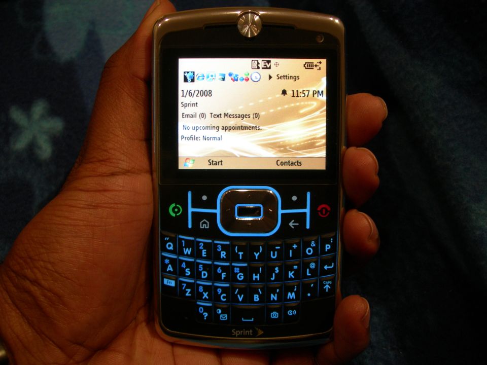 Motorola Q phone with QWERTY keyboard and illuminated screen held in a hand