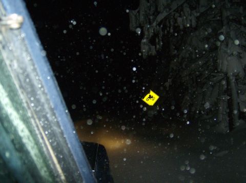 1986 Ford Bronco - ATV warning sign seen through a snowy windshield at night.