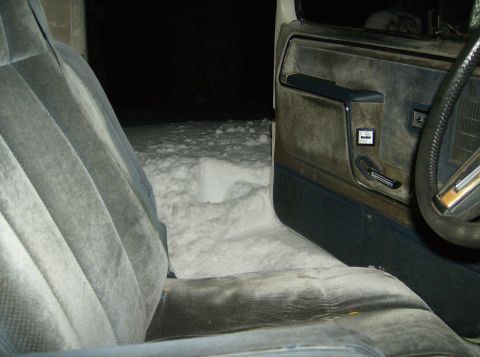 1986 Ford Bronco - The interior of a vehicle is shown with snow covering the ground outside and inside the vehicle.