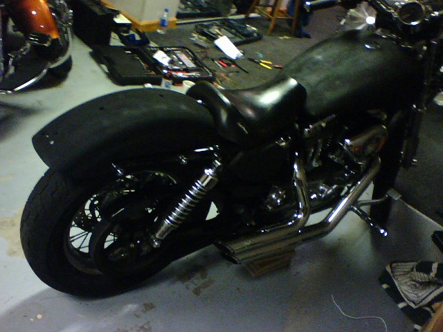 Black motorcycle rear fender and wheel with chrome shocks and exhaust