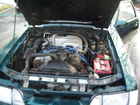 1991 Ford Mustang - The engine bay of a 1991 Ford Mustang is visible with the hood open, revealing the V8 engine and associated components.