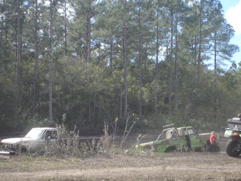 1989 Ford Bronco - Two trucks are stuck in the mud during an off-road event.