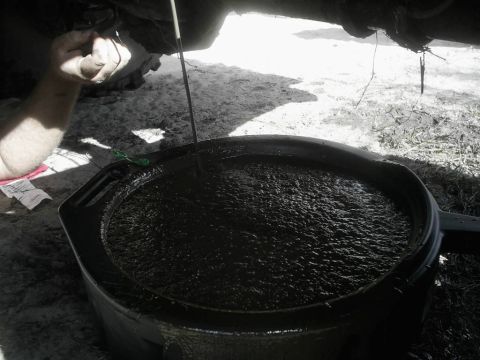1989 Ford Bronco - Someone is performing an oil change on a vehicle, collecting the old oil in a large black pan.