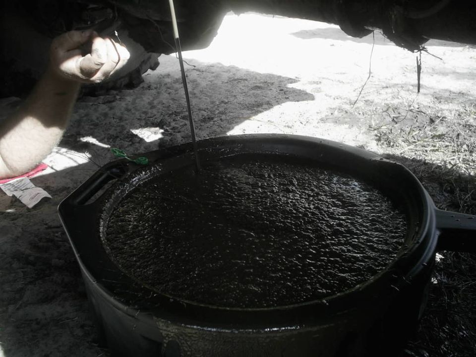 draining dirty oil into a pan, hand reaching up to the oil plug