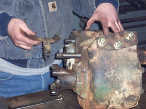 1978 Ford Bronco - A mechanic works on a rusty transfer case, with a wrench visible on the workbench.