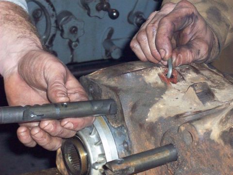 1978 Ford Bronco - Close-up of hands performing maintenance on a vehicle's transfer case.