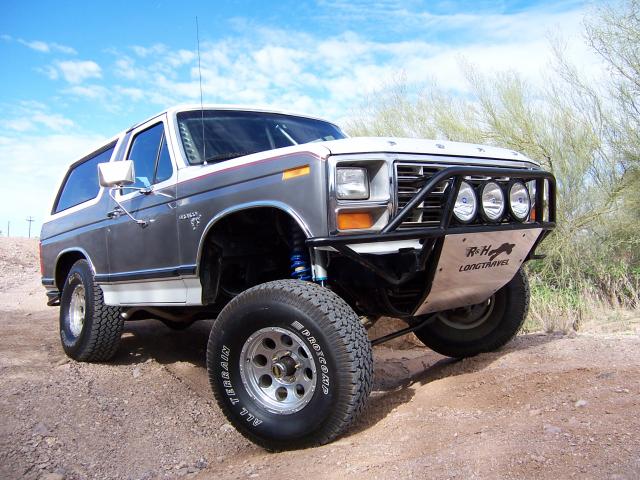 Gray and white 1980 Ford Bronco with off-road modifications, front three-quarter view, lifted suspension, aftermarket bumper with lights