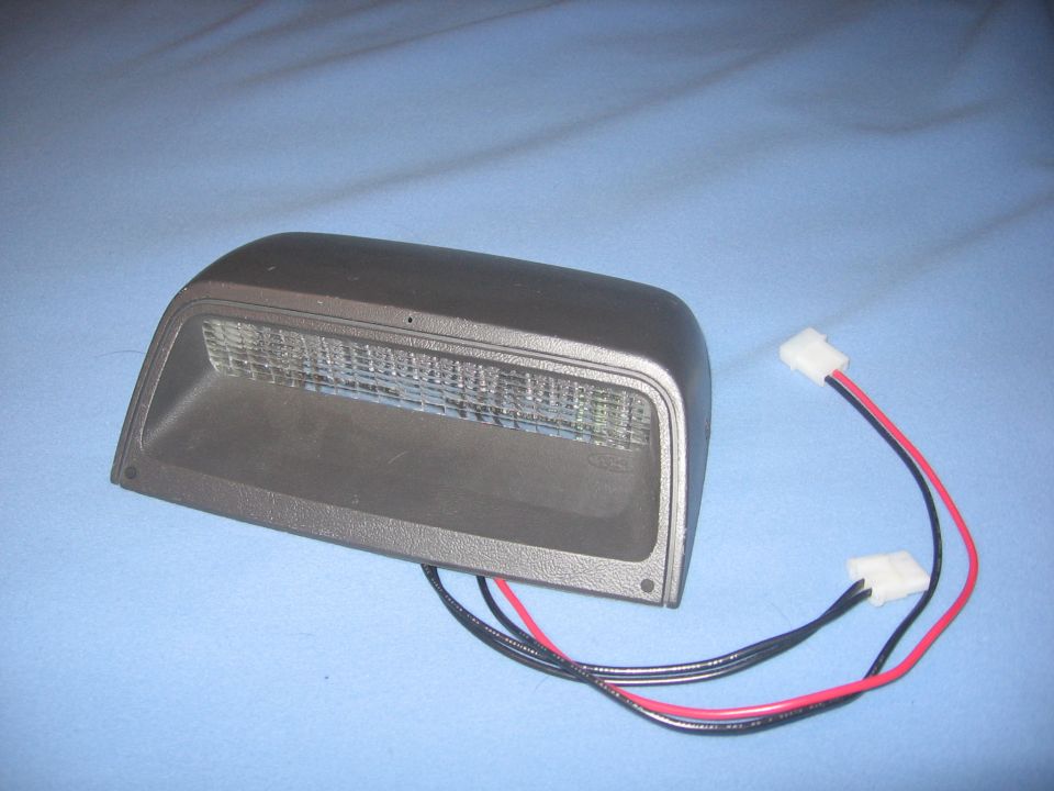 Car part, possibly a light, with red and black wires attached