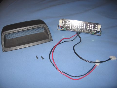 2000 Ford Crown Victoria - Disassembled interior light assembly with housing and LED board.