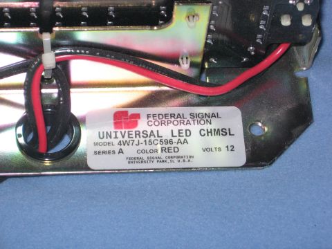 2000 Ford Crown Victoria - Close-up of a Federal Signal Corporation Universal LED CHMSL part, model 4W7J-15C596-AA, in red, with 12 volts indicated.