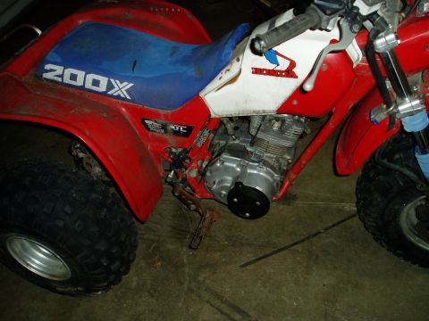 2000 Ford E350 - A red and blue Honda 200X three-wheeler is parked indoors, showing its engine and rear wheel.