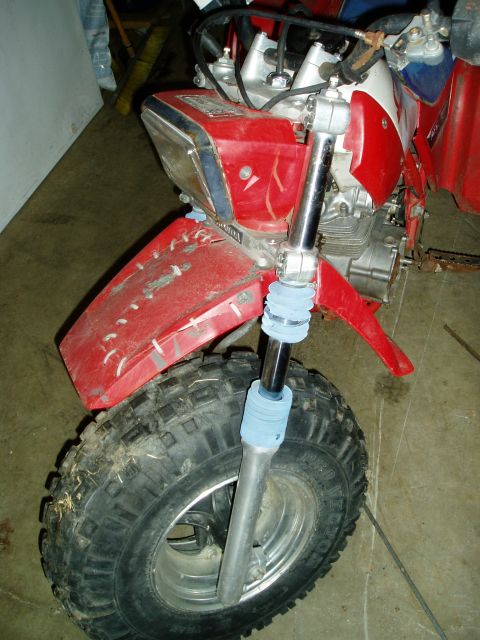 2000 Ford E350 - Front view of a red three-wheeled ATV, showing the tire, suspension, and headlight assembly.