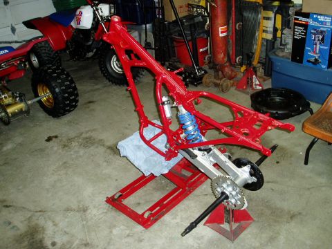 2000 Ford E350 - Motorcycle frame on a stand in a garage with other vehicles and tools visible.