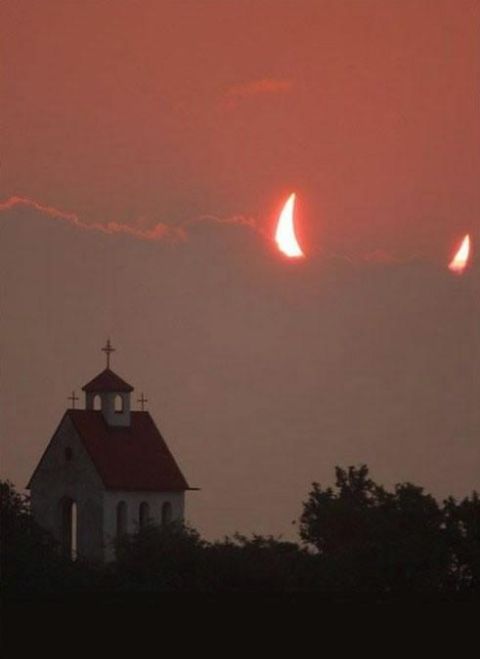 1988 Mercury Grand Marquis - A partial solar eclipse is visible in the sky above a small church and silhouetted trees.