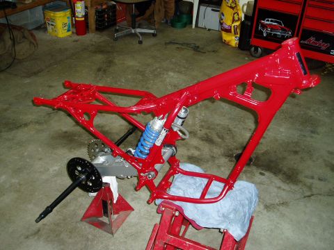 2000 Ford E350 - A red motorcycle frame is disassembled and supported by red jack stands in a garage.